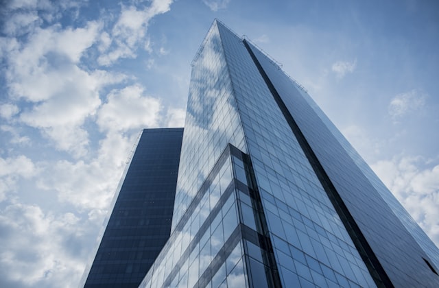A modern glass corporate tower against a cloudy sky