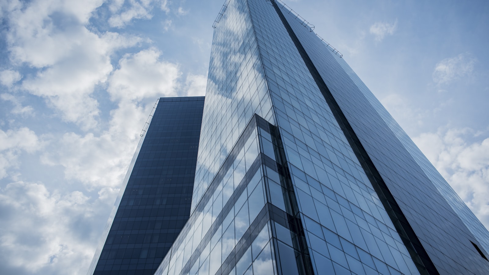 A modern glass corporate tower against a cloudy sky