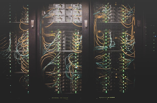 A dark data center server rack with cabling and status lights