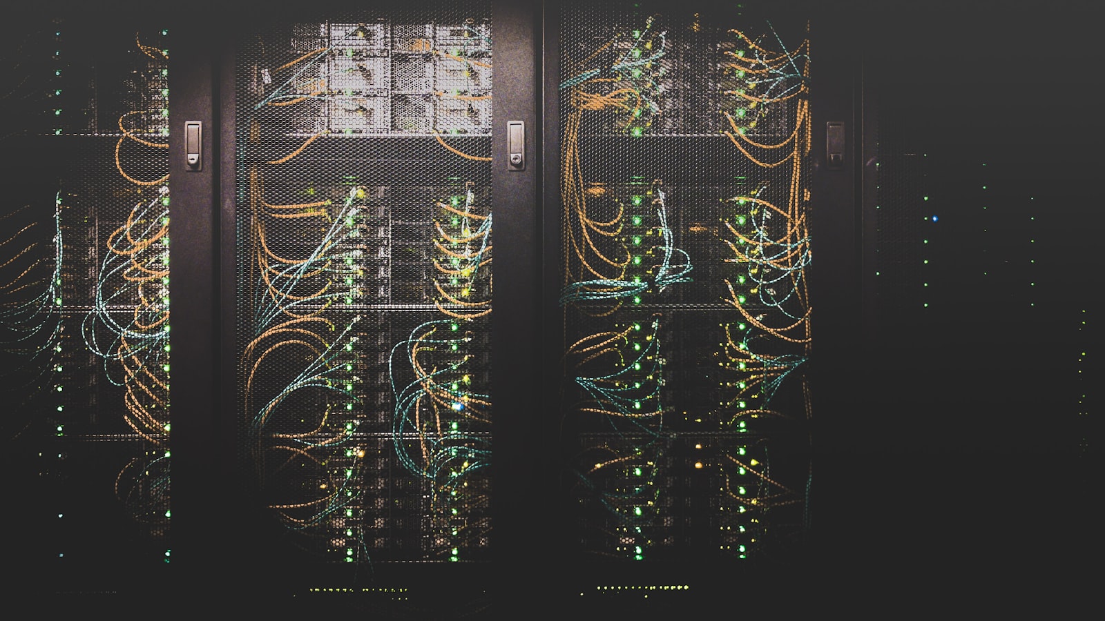 A dark data center server rack with cabling and status lights